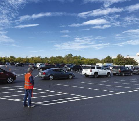 David Watson helped to direct vehicles as they lined up in a winding fashion on the Sulphur Springs High School parking lot before reaching the food distribution site. Staff photos by Enola Gay Mathews