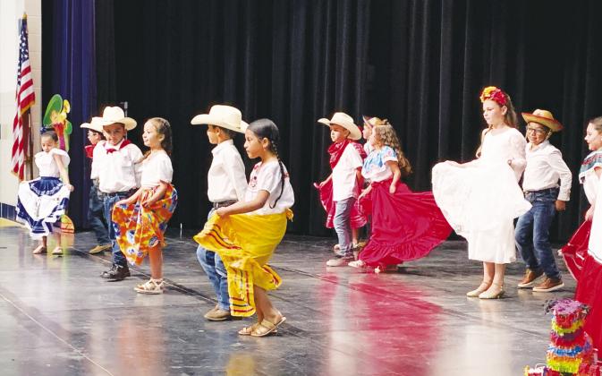 Travis Primary School students in the Dual Language Enrichment Program are a swirl of color as they kick up their feet performing traditional Mexican dances as part of their Cinco de Mayo program Friday, May 3. The Sulphur Springs Middle School cafeteria was packed with parents, staff and friends clapping and cheering at the festive program. Staff photo by Faith Huffman