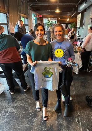 Erika Mayorga and Earth Day assistant Sissy Gortmaker display the Earth Day T-shirt, free to visitors at the event.
