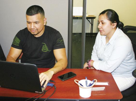 GETTING READY —Paris Junior College-Sulphur Springs Center Education Advisor Maria Zuniga, right, observes as Pedro Mendoza completes form to enroll for the spring semester. For information about classes and registration requirements, call 903-885-- 1232.