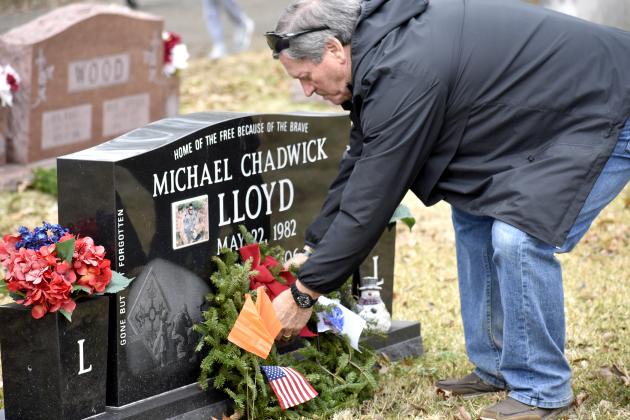 Jimmy Lloyd, husband of organizer Dena Lloyd, sets an evergreen wreath at the grave of their son, Michael Lloyd, at the Wreaths Across America wreath-laying event in Sulphur Springs’ City Cemetery Saturday morning. The nation-wide event honors the sacrifice and service of deceased U.S. military veterans. This year, Dena Lloyd raised funding for more than 700 wreaths to place in City Cemetery and Mel Haven Cemetery. Staff photo by Jillian Smith