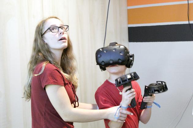Jenna Rackel, 16, assists Seven Riegel, 10, both of Sulphur Springs, and watches his progress on a monitor mounted above the space, while Seven tries out the virtual reality gaming system at VRSocial on Spring Street in Sulphur Springs. The VR arcade is set to open next week. Staff photos by Jillian Smith