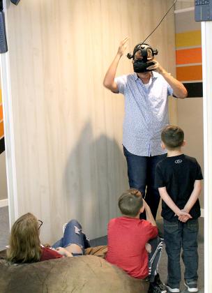 Scott Hansen (standing) talks (from left) Jenna Rackel, 16, Seven Riegel, 10, and Jaxon Maddox, 6, all of Sulphur Springs, through an orientation of the virtual reality gaming equipment at VRSocial arcade, which is set to open next week on Spring Street in Sulphur Springs. Staff photo by Jillian Smith