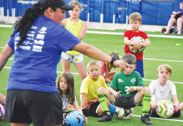 Young campers take a short break and listen to instruction from a coach at the recent Sulphur Springs soccer camp held in the high school multi-purpose building. Staff photos by Don Wallace