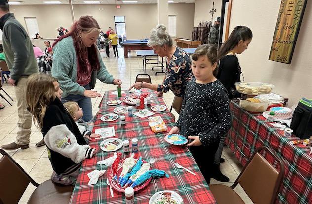 Salvation Army volunteer Beverly Haygood, center, points out supplies of frosting and sprinkles on the cookie decorating table at the Breakfast with Santa event held at The ROC.