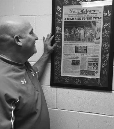 Coach Owens looks over articles in the Sulphur Springs News-Telegram covering the state champion football run and title game held in San Antonio.