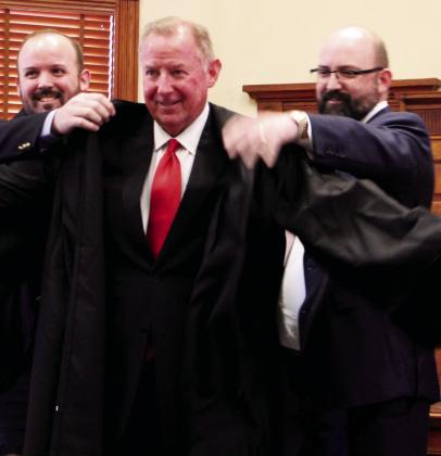 John Ginn's sons Charlie and Andy Ginn are pleased to help their dad officially put on his robe after Ginn was sworn in as the new Hopkins County Court-At-Law Judge Tuesday morning, Jan. 2, 2024. Ginn was selected by Hopkins County Commissioners Court to fill the seat after Clay Harrison tendered his resignation in order to start a private practice. Staff photo by Tammy Vinson