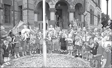 Tuesday, July 3, 2007: Children from “His Kids” Learning Center at Fellowship Christian Church stand in attention, with raised heads and raised flags, covering their hearts as they honor the American flag with the Pledge of Allegiance in front of the Hopkins County Courthouse. “His Kids” banded together for a “Freedom March” at VF Outlet and around the downtown square, visiting businesses along their march to wish all a “Happy Independence Day.” Archive