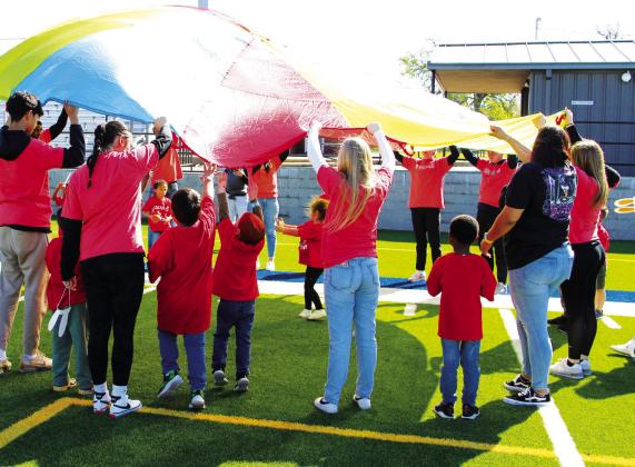 Sulphur Springs Head Start (at right) and pre-kindergarten students (top, right), accompanied by their Key Club buddies, rotated through various activity stations set up on the football field, including the parachute exercise at right. Staff Photo by Tammy Vinson