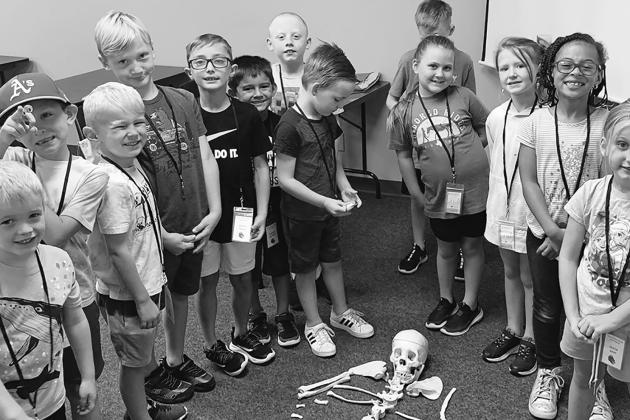 CURIOUS YOUNGSTERS —Children from last year's PJC Kids College are shown having a great time posing with a skeleton. Submitted photo