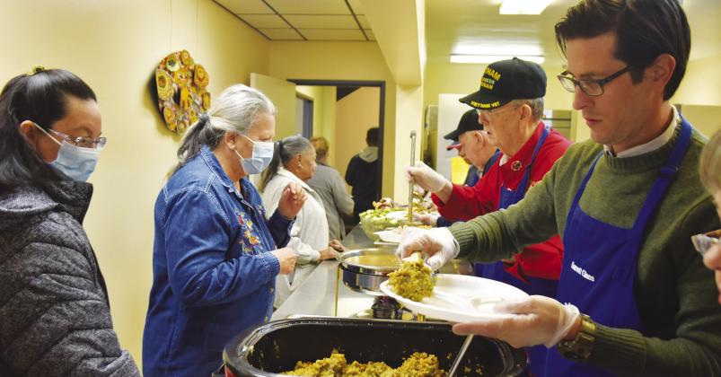 INDOOR DINING — Garrett Glass (right) of the Knight of Columbus from St. James Catholic Church, serves a Thanksgiving meal at the First Methodist Church Dinner Bell to in-person diners for the first time in more than two years. Meals have been packaged to-go since Covid-19 restrictions were in place. No meal will be served by Dinner Bell on Nov. 23 to allow volunteers to spend time with their families. Staff photo by Don Wallace