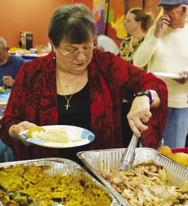 GREAT TIME — Nola Rae Tadlock partakes of some Thanksgiving treats. She said she is thankful 'to get out of the house and come to the Senior Citizens Center.' Staff photos by Don Wallace