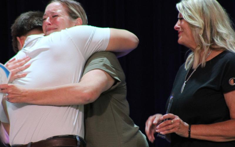 Austin Guy gives Cassie Mund-Burns and Elaine Mund a hug after receiving the Kaleb Mund Memorial Scholarship.
