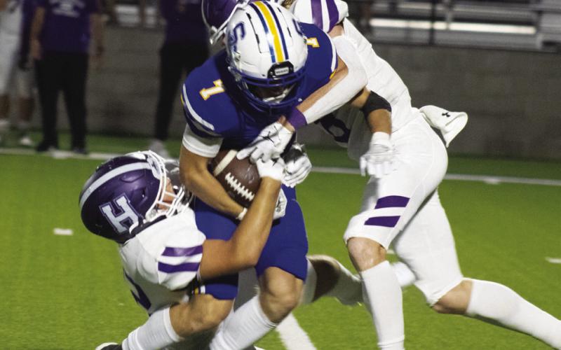 POWERING THROUGH — Jaxson Haire (7) powers his way through a pair of defenders during earlier home action. Haire had an outstanding performance in the Wildcats' 36-7 win over Community Friday, catching four passes for 113 yards and scoring two touchdowns. Photo by DJ Spencer