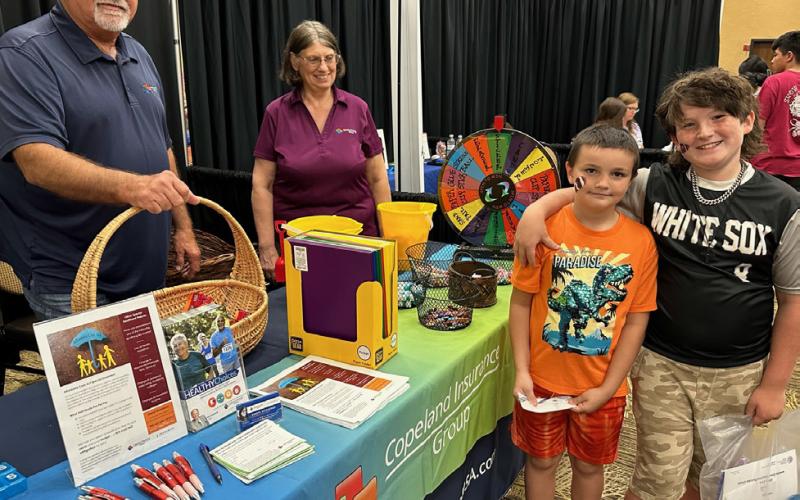 (Front) Stetson and Jaydin Taylor spin the game wheel manned by Sheryl Dickenson at the Jay Copeland Insurance booth during the 2023 CANHelp Back to School Fair on Thursday, July 27, 2023, at Hopkins County Regional Civic Center.