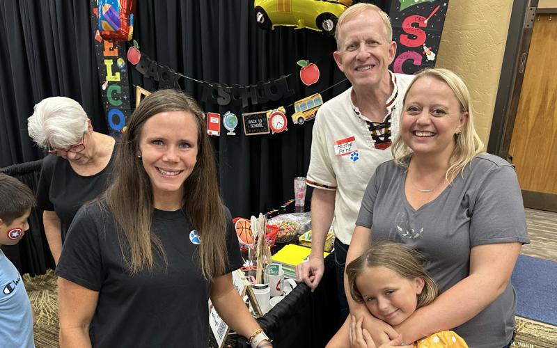 Whitney Vaughn, Pastor Pete McNabb, and Bethany and Charlotte Ferrall are at the First United Methodist Church game booth, where (back left) Pam Sellers awards a prize.