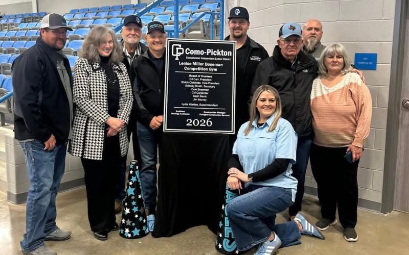Como-Pickton CISD Superintendent (second from left) Lydia Walden and CPCISD Trustees (from left) D.J. Carr, Keith Monk, Shiloh Childress, Cole Boseman, Jim Murray and Clif Carpenter, and (kneeling) Brittney Smith Board member with (far right) CPCISD Business Manager Lenise Boseman, at the dedication for the new Como-Pickton CISD Lenise Miller Boseman Competition Gym, named in honor of Boseman's 52 years with the district. CPCISD photo