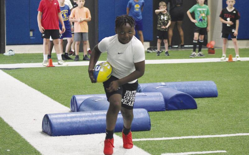 A young camper runs with the ball during a footwork drill at Wildcat Football Camp. The camp was held May 26-28 in the Multipurpose Building.
