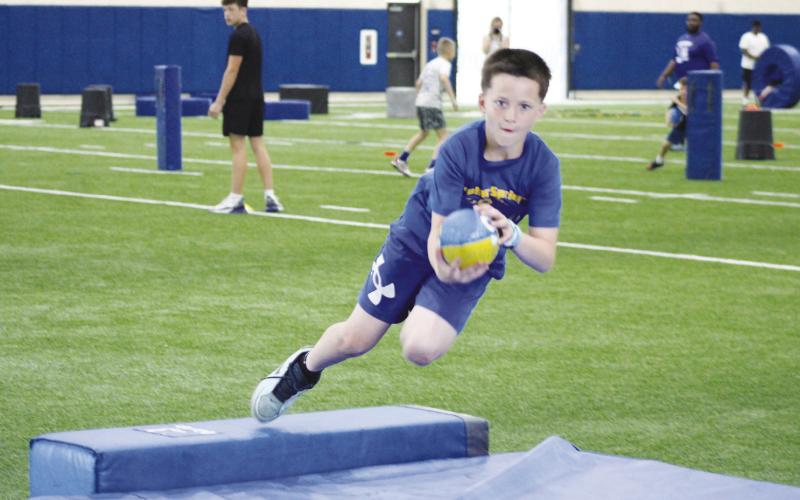 A camper makes a diving catch during a catching drill at Wildcat Football Camp. The catching drill was one of the most popular ones among campers.