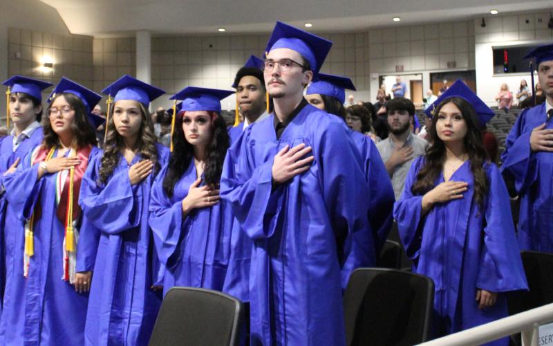 Austin Academic Center 2026 graduate candidates place their hands on their hearts for the singing of National Anthem and Pledge of Allegiance. Staff photo by Faith Huffman