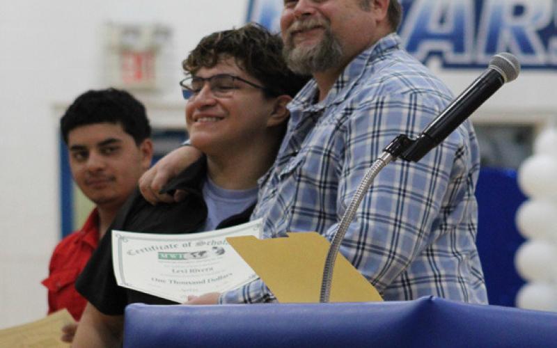 Agriculture teacher Sam Stanley gives Roque “Levi” Rivera a hug while presenting him and Ricardo Estrada with $1,000 Scholarships from Missouri Welding Institute.