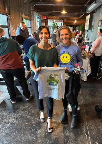 Erika Mayorga and Earth Day assistant Sissy Gortmaker display the Earth Day T-shirt, free to visitors at the event.