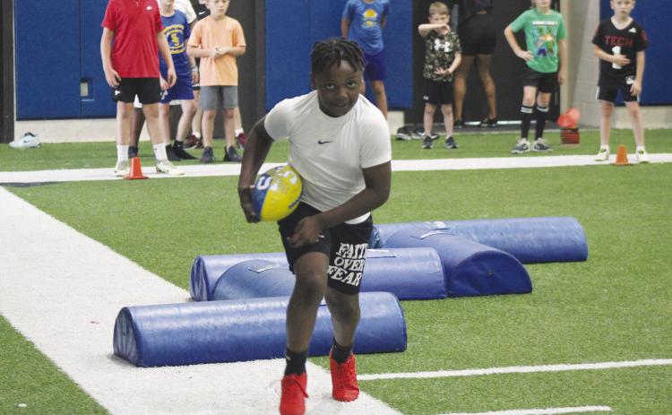 A young camper runs with the ball during a footwork drill at Wildcat Football Camp. The camp was held May 26-28 in the Multipurpose Building.